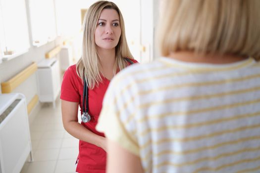 Doctor communicating with female patient in clinic. Quality medical care concept