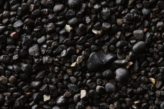 Texture of black volcanic sand for background. Black Sand beach macro photography. Close-up view of volcanic sand surface. Icelandic Black Sand macro photography. Black pebble background.