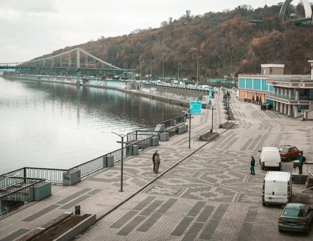 Kyiv, Ukraine, November, 2020. Capital of Ukraine, evening on the Dnipro river bank with people walking and parked cars. Kivv river station. High quality photo.