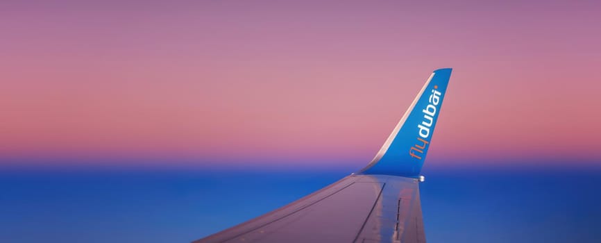 Wing of the FlyDubai airplane during a flight. Winglet of an airliner against the background of the dawn sky. 27.01.2022 Dubai.