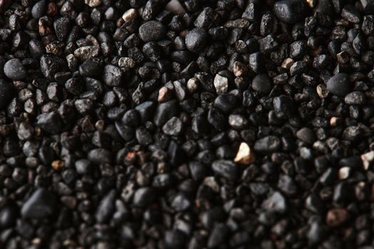 Texture of black volcanic sand for background. Black Sand beach macro photography. Close-up view of volcanic sand surface. Icelandic Black Sand macro photography. Black pebble background.