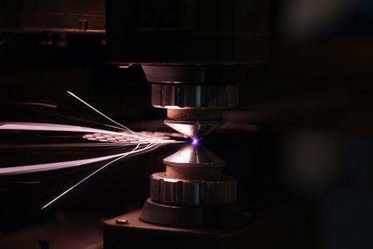 Laser machine cutting sheet of metal with bright sparks closeup. Metalworking concept