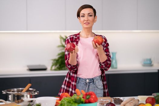Woman with fruits in hands standing in kitchen. Young happy woman choosing fruits for her healthy life style eating. Nutrition concept. Organic food concept Healthy food concept.