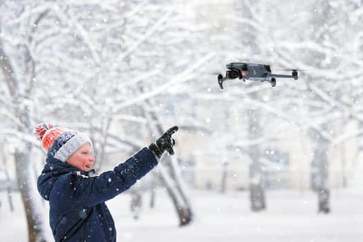 Teenager boy dressed winter jacket and modern digital drone DJI Mavic, flying in snow conditions. DJI Mavic 3 most portable drones with Hasselblad camera. 25.01.2022 Rostov-on-Don, Russia.