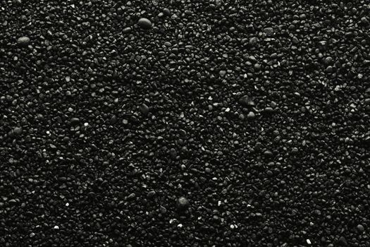 Texture of black volcanic sand for background. Black Sand beach macro photography. Close-up view of volcanic sand surface. Icelandic Black Sand macro photography. Black pebble background.