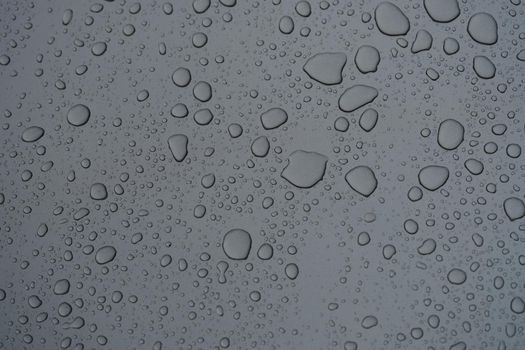 Raindrops on dark glass on rainy day closeup background. Weather forecast concept