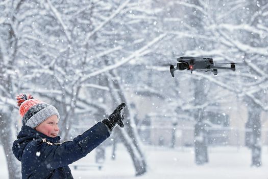 Teenager boy dressed winter jacket and modern digital drone DJI Mavic, flying in snow conditions. DJI Mavic 3 most portable drones with Hasselblad camera. 25.01.2022 Rostov-on-Don, Russia.