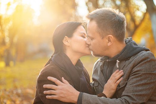Couple In Love Kissing in the Sun Shining. Husband and His Wife Kissing on a Sunny Meadow in the Autumn Forest. Close-up. Fall Background. High quality photo