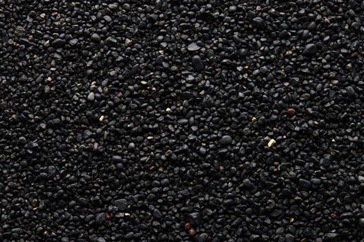 Texture of black volcanic sand for background. Black Sand beach macro photography. Close-up view of volcanic sand surface. Icelandic Black Sand macro photography. Black pebble background.