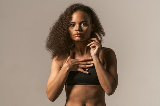 Woman power activist African American girl with afro hair standing in black bare shoulder top isolated on grey background. Human emotions, facial expression concept.
