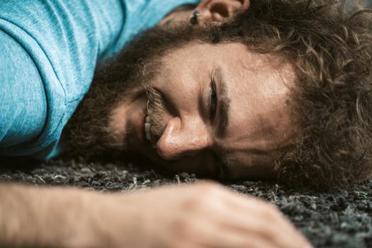 Happy exhausted home exercise man laying on the carpet and resting. Funny disheveled hair man doing exercise at home. Tired young man doing exercises at home on quarantine. Concept of healthy life.