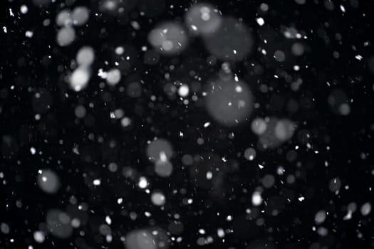 Snowfall on black background. Snowfall in the night sky, real snowflakes fall in the night.