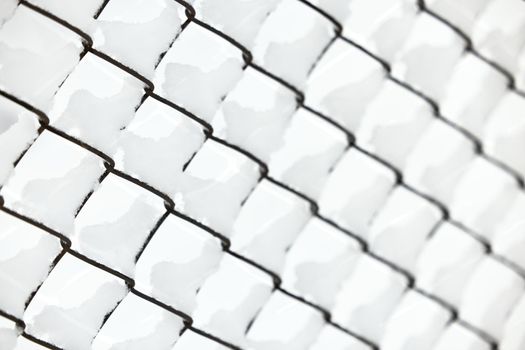 Snow on a mesh fence close-up, snow fence. Abstract winter background. Snow on a wire fence.