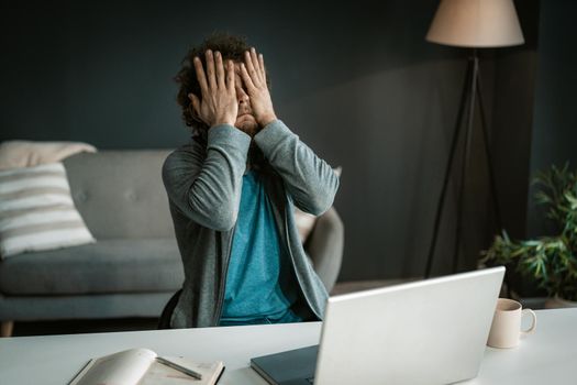 Online Business Owner Has an Eyes Ache After a Hard Working Day with a Computer. Man Covers His Eyes With His Hands After Looking at the Laptop Screen for a Long Time. Close-up. High quality photo