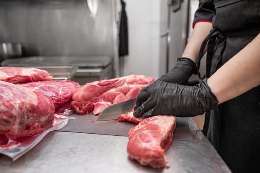 Close up of raw meat and woman butcher cutting meat with knife. High quality photo