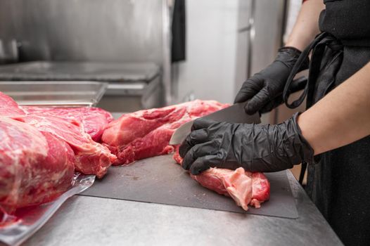 Close up of raw meat and woman butcher cutting meat with knife. High quality photo