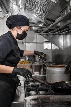 Side view of female chef working in commercial kitchen. High quality photography