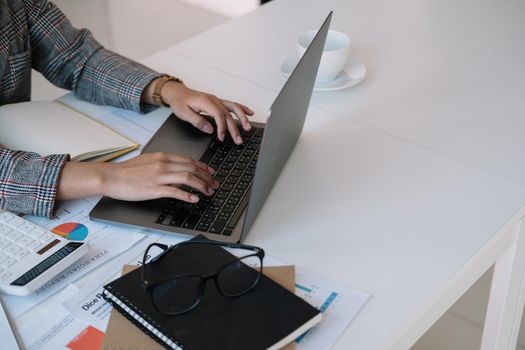 Close up businesswoman using laptop, typing on keyboard with documents, writing email, accountant writing financial report, busy student studying online, searching information