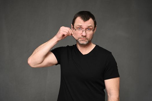 portrait of an adult man in a black t-shirt with glasses shows creative