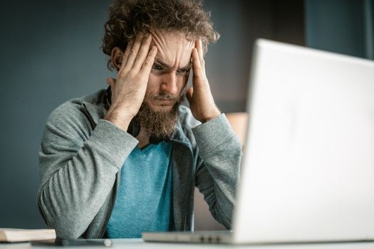 Young Man Looks at the Screen of his Laptop Very Attentively. Remote Work During the Quarantine Period. Online Study. Close-up Portrait . High quality photo