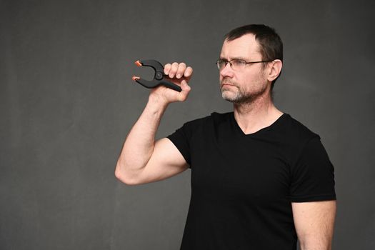 side view portrait of a serious man in glasses holding a tool in his hand