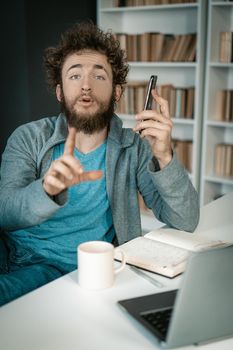 Businessman Has a Very Important Phone Call and Asks to be Quiet. Man Has an Important Call at Work. Close-up. Bookshelves Background. High quality photo