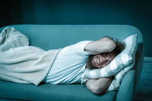 Lazy Guy Refuses to Get up Early in the Morning for Work. Man Lies on the Couch Covered with a Blanket At Home. Close-up. High quality photo