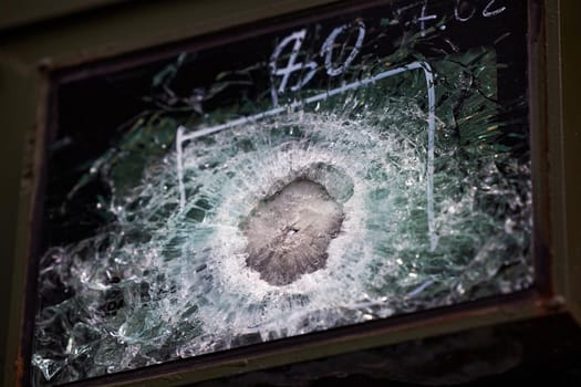 Armored glass after of a direct hit from an automatic weapon. Safety glass after being hit by a bullet. Bulletproof glass armored car after gunshot.