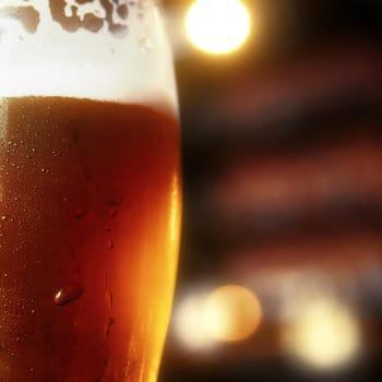 Glass of beer on a table in a bar on blurred bokeh background.