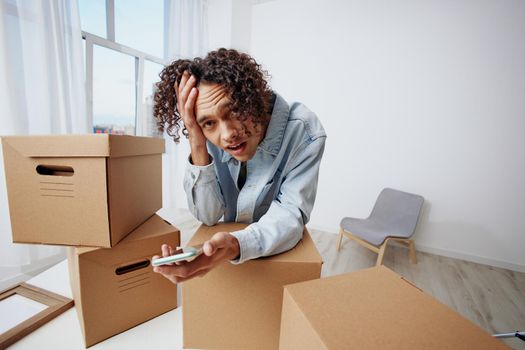 A young man unpacking things from boxes in the room interior. High quality photo