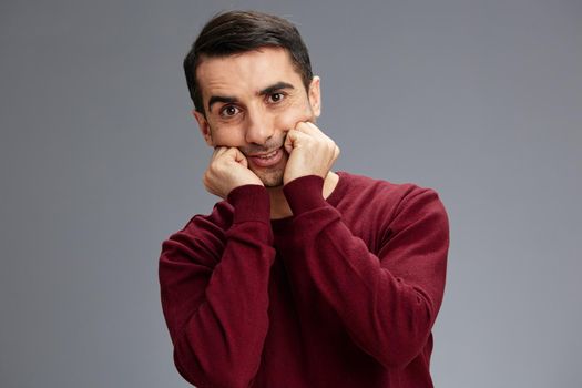 successful man stretches mouth with hands smile posing red sweater elegant style. High quality photo