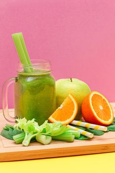 Fresh Green Smoothie of Apple, Celery, Spinach and Orange in Glass Smoothie Jar with Yellow Cocktail Straw on Wooden Cutting Board. Vegan Detox Drink. Vegetarian Culture. Healthy Eating and Fruit Diet