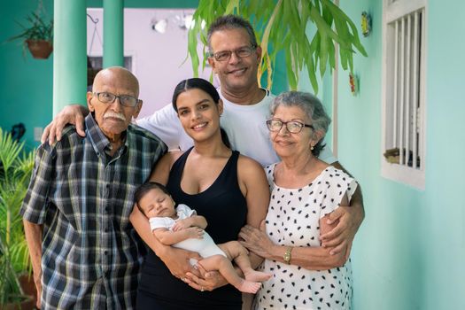 Photo of a group of people. A baby in the arms of a young woman, a man and an elderly couple