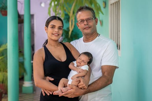 Photo of a baby in the arms of a young woman and a man by her side