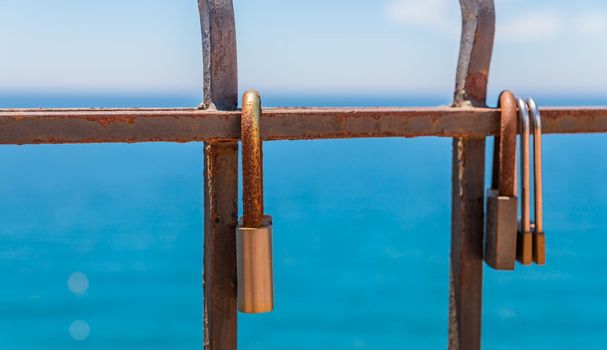 rusty padlock attached to a balustrade by the sea, a traditional way of showing love, relationship