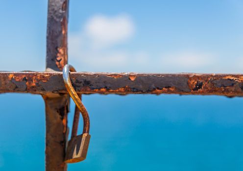 rusty padlock attached to a balustrade by the sea, a traditional way of showing love, relationship