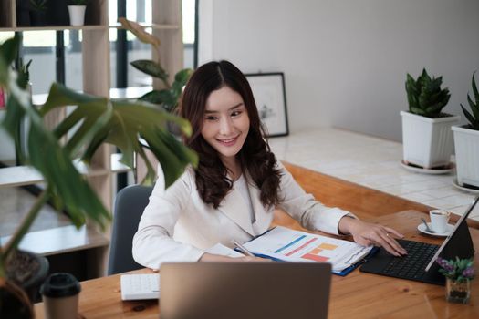 Portrait of Busy Asian Secretary smiling and waiting customer while working at office. Business Finance concept