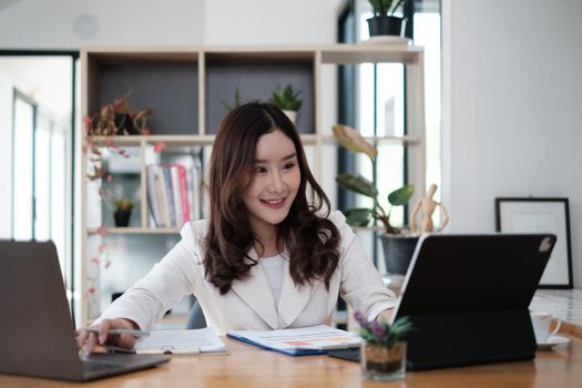 Portrait of Busy Asian Secretary smiling and waiting customer while working at office. Business Finance concept