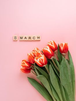 International women's day or eight march concept with copy space. 8 march text and bunch of red tulip on pink background. Top view or flat lay. Aesthetic background for 8 march women's day. Vertical