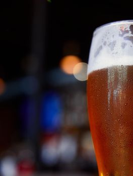 Glass of beer on a table in a bar on blurred bokeh background.