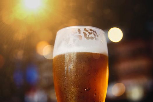 Glass of beer on a table in a bar on blurred bokeh background.