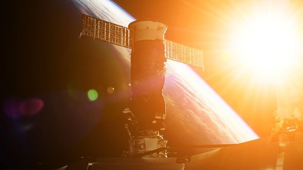 View on ISS Progress resupply ship, View out from a passenger window on the SpaceX Crew Dragon. Docking maneuver near the Space Station. Elements of image furnished by NASA.