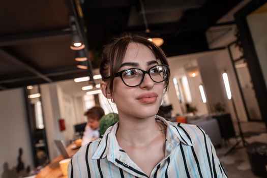 Portrait of businesswoman in casual clothes with glasses at modern startup open plan office interior. Selective focus. High-quality photo