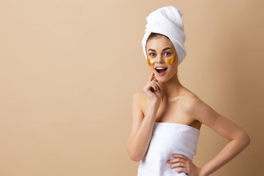 young woman with a towel on his head gesturing with his hands skin care beige background. High quality photo