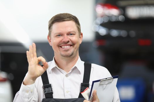 Portrait garage service worker show ok sign with hand and happily smiling in uniform. Man provide high quality machine service. Pit stop, good job concept