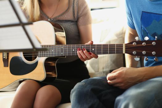 Close-up of female teacher explain notes to client on guitar instrument, music class at home. Female teach chords and new song. Music, art, hobby concept