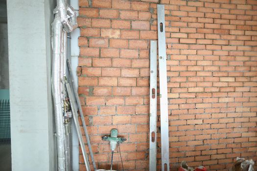 Close-up of red brick wall with water supply, new plastic pipes on concrete wall of house. Renovation works on new building object. Construction concept