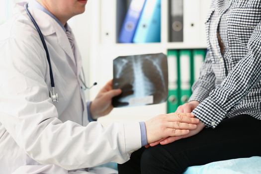 Close-up of qualified male doctor hold x ray scan of patients lungs and talk to client. Medical worker prescribe full diagnostic for woman. Disease concept
