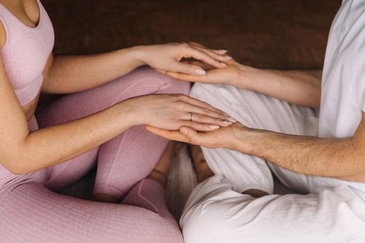 a woman and a man are engaged in pair meditation holding hands in the gym.