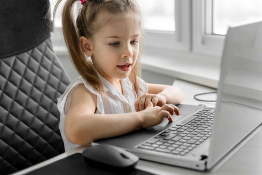 cute little caucasian girl studying online at home. children video conference with teacher tutor at home